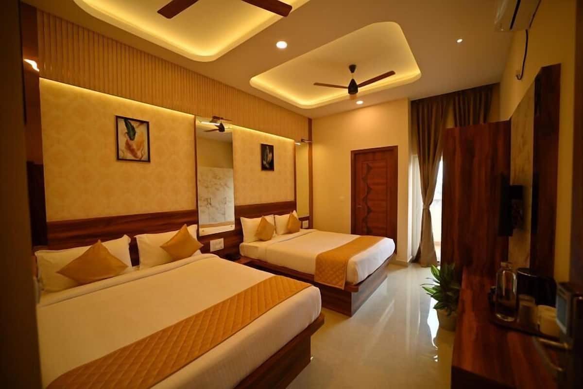 A hotel room with two beds, a ceiling fan, a TV, and a wooden wardrobe.