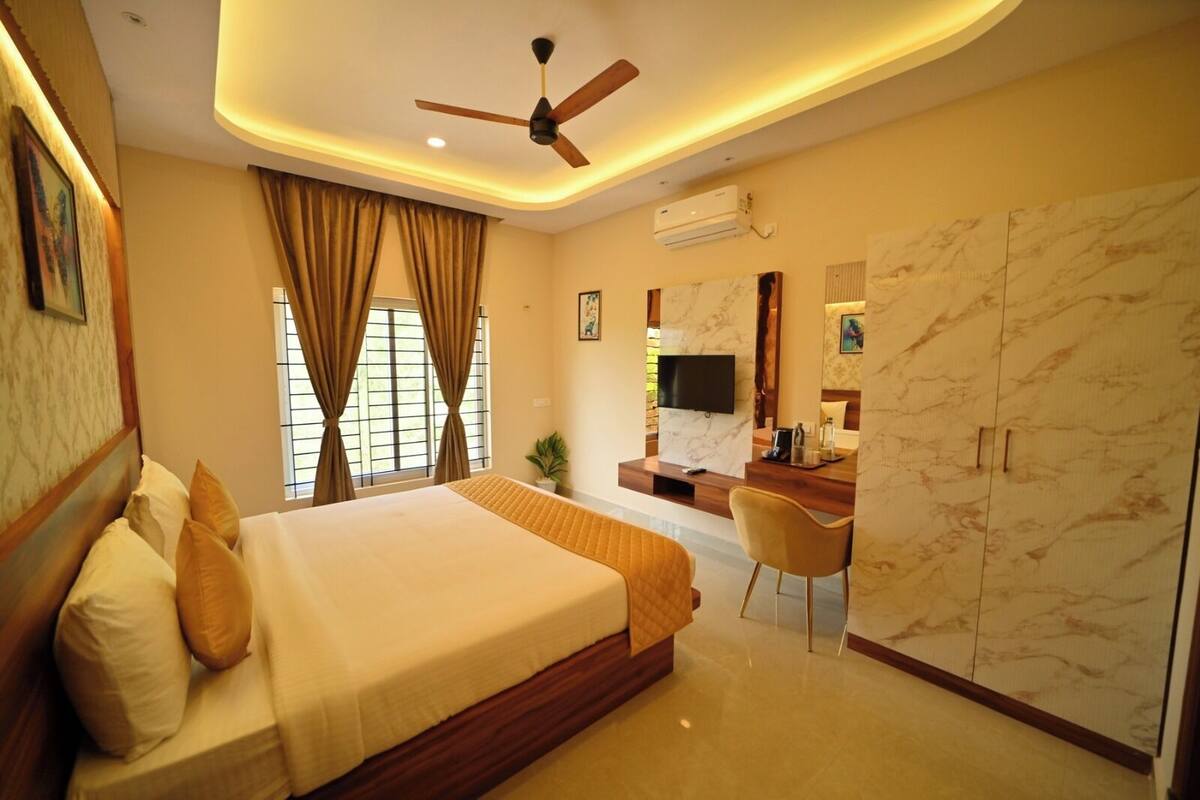 A hotel room with a large bed, a desk, a TV, and a wardrobe.