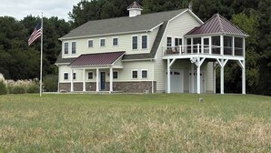 A two-story house with a balcony, a stone foundation, and a flag. - NEW KI Creek Retreat! 3BR/2bath water view, private house near KI wedding venues (Stevensville)