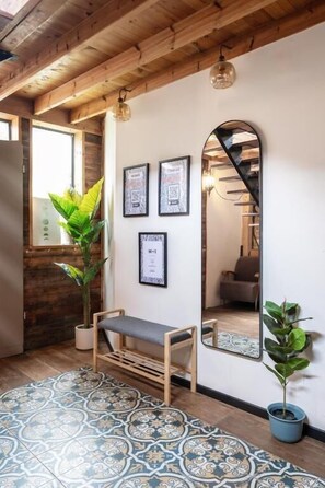A room with a wooden ceiling, a bench, a potted plant, and a wall with framed pictures.