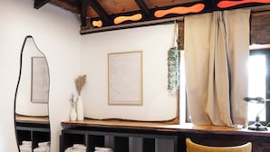 Un dormitorio con una cama, un escritorio, una silla, un espejo y una planta colgante.