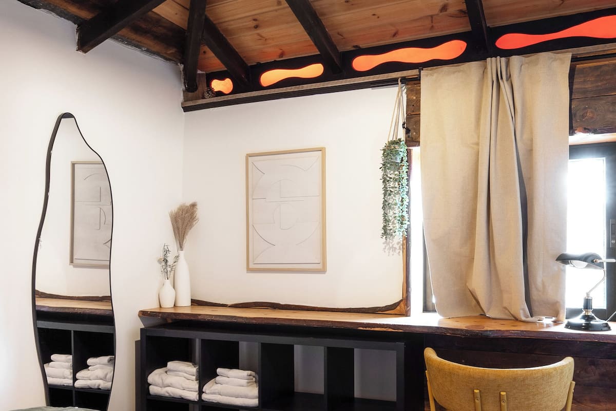 Un dormitorio con una cama, un escritorio, una silla, un espejo y una planta colgante.