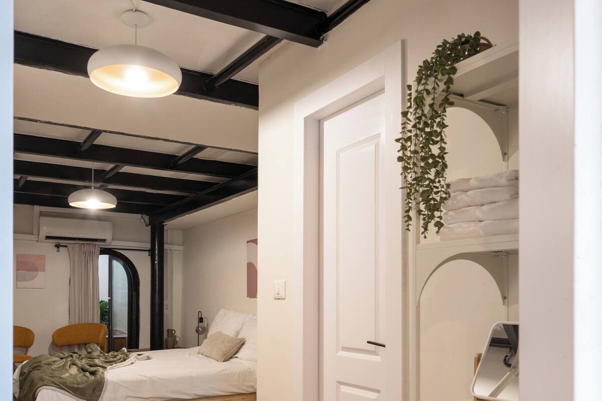 Un dormitorio con cama, una planta colgante, un armario y una lámpara en el techo.
