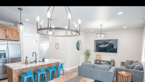 A modern kitchen with a central island, blue bar stools, and a chandelier. - Ashton Escape - Newly built townhome near Yellowstone/Grand Tetons/Island Park (Ashton)