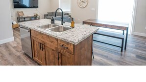 A modern kitchen with a central island, built-in appliances, and a large window. - Ashton Escape - Newly built townhome near Yellowstone/Grand Tetons/Island Park (Ashton)