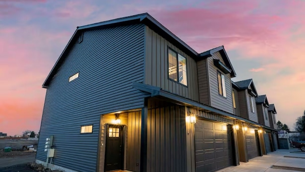 A modern two-story house with a garage, a driveway, and a well-lit entrance. - Ashton Escape - Newly built townhome near Yellowstone/Grand Tetons/Island Park (Ashton)