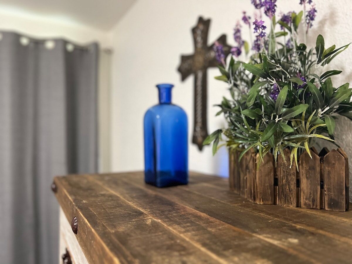 A wooden table with a blue vase and a plant.