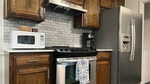 Una cocina con armarios de madera, un refrigerador de acero inoxidable, un microondas y una estufa.