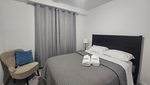 Une chambre d’hôtel avec un lit, une chaise, une lampe et une paire de serviettes posées sur le lit.