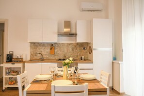 A modern kitchen with white cabinets, a granite countertop, and a dining area set for four.