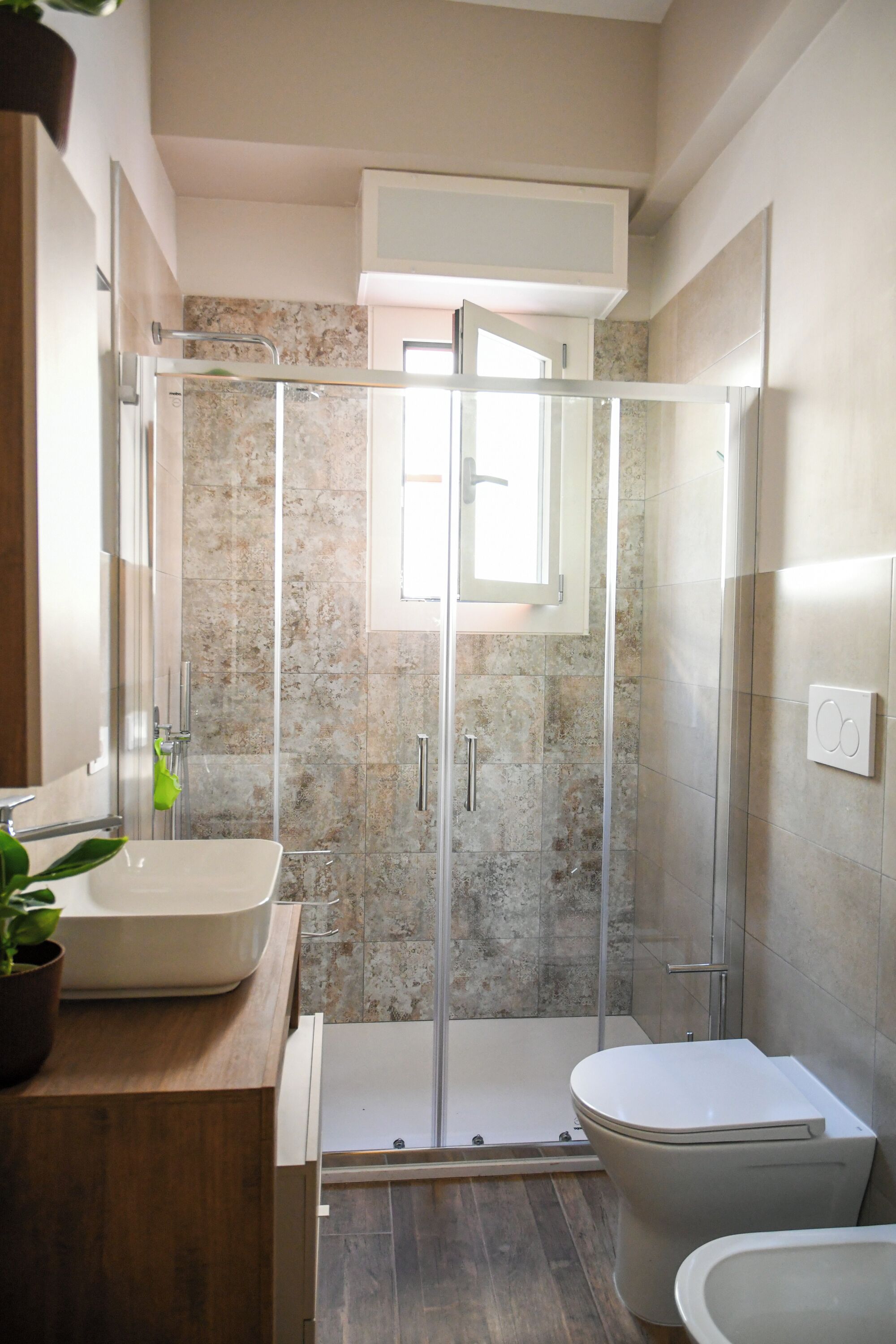 A modern bathroom with a glass-enclosed shower, a white sink, and a toilet.