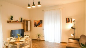 A dining area with a wooden table set for four, white chairs, and a small potted plant on a side table. - House MoniK - Apartment 1 (Brindisi)