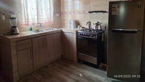 Une cuisine équipée d’une cuisinière, d’un réfrigérateur et d’un mixeur.