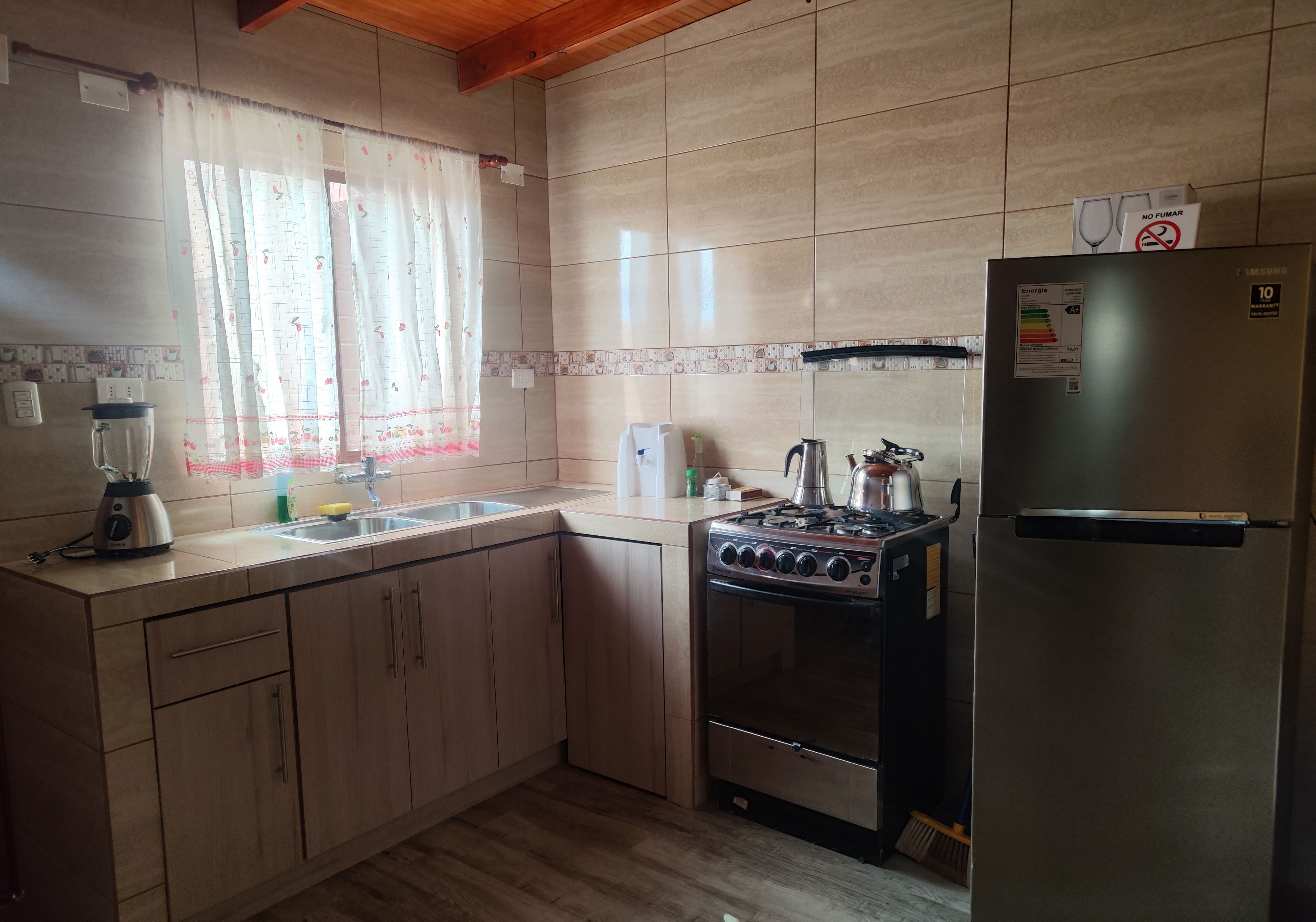 A kitchen with a stove, refrigerator, and a blender.