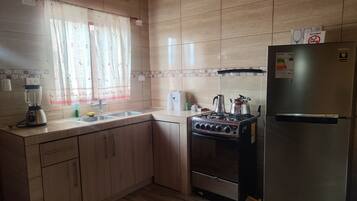A kitchen with a stove, refrigerator, and a blender.