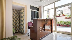 A reception area with a wooden desk, a red chair, and a glass partition.