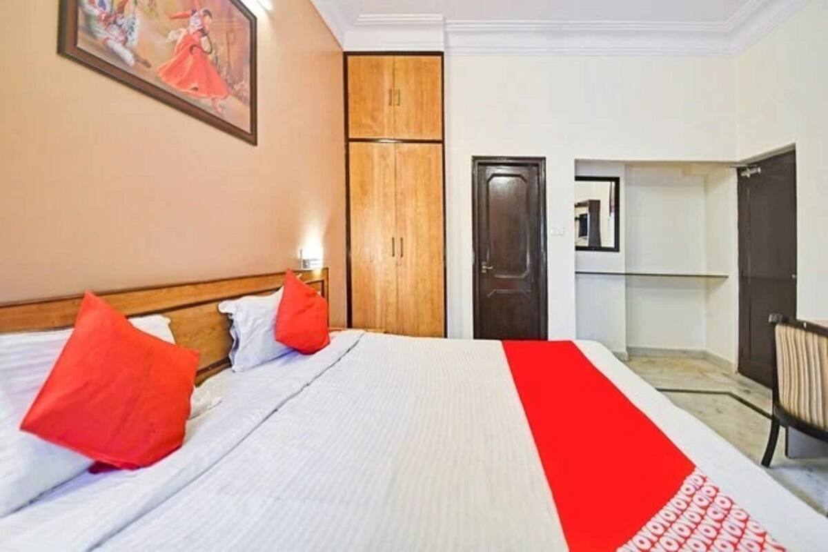 A hotel room with a bed, a wardrobe, a desk, and a chair.