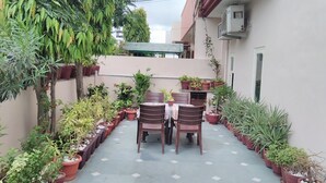 A patio with a table and chairs, surrounded by potted plants.