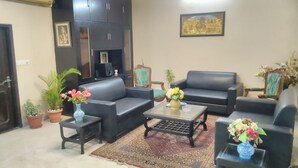 A living room with two black sofas, a coffee table, and potted plants.