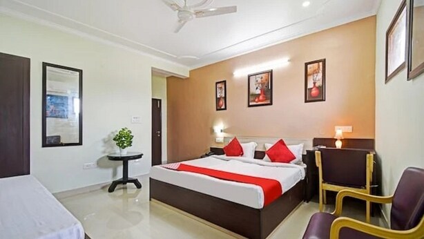 A hotel room with a bed, bedside tables, a chair, and a ceiling fan.