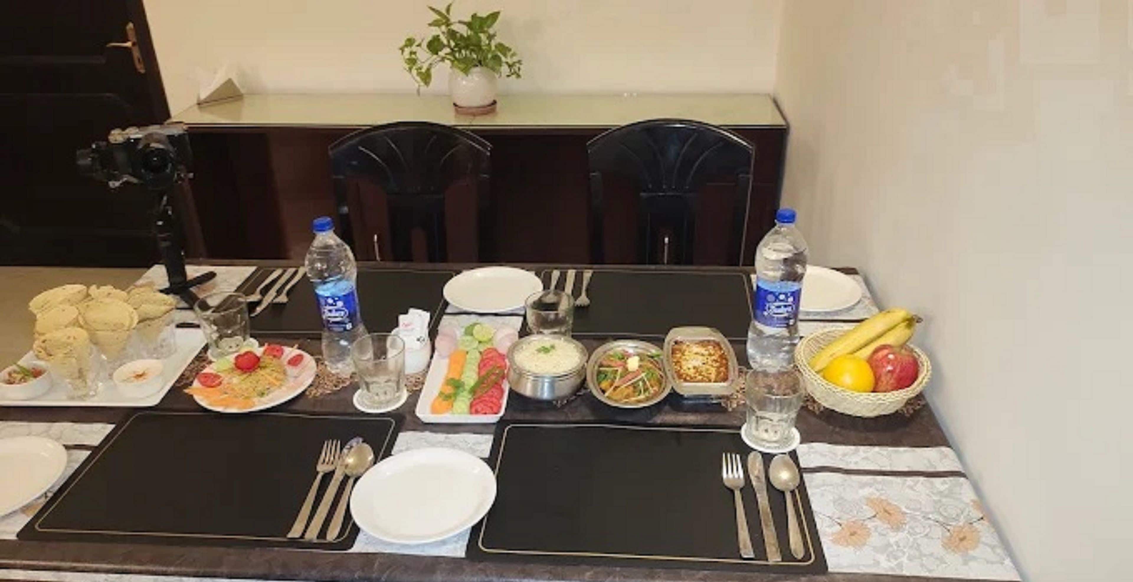 Una mesa de comedor dispuesta con diferentes platos, botellas de agua y cubiertos.