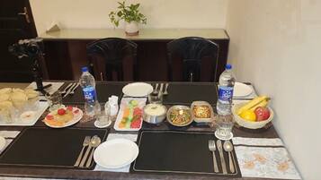 Una mesa de comedor dispuesta con diferentes platos, botellas de agua y cubiertos.