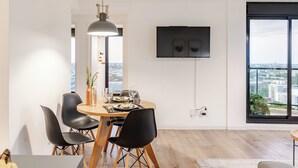 A modern dining area with a round table, black chairs, a pendant light, and a flat-screen TV mounted on the wall. - Penthouse | Unbeatable Views | 24-Hour Concierge | Outdoor Gym | Pet-Friendly (Montevideo)