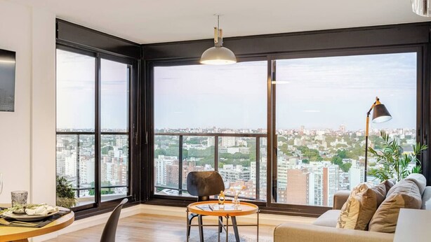A modern living room with a large window, a round table, a sofa, and a floor lamp. - Penthouse | Unbeatable Views | 24-Hour Concierge | Outdoor Gym | Pet-Friendly (Montevideo)