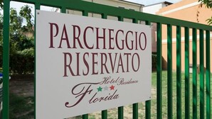 A sign for "Parcheggio Riservato Hotel Residence Florida" with a green metal fence.