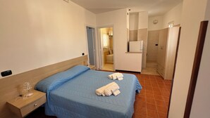 A hotel room with a bed, a bedside table, a wardrobe, and a bathroom visible through an open door.