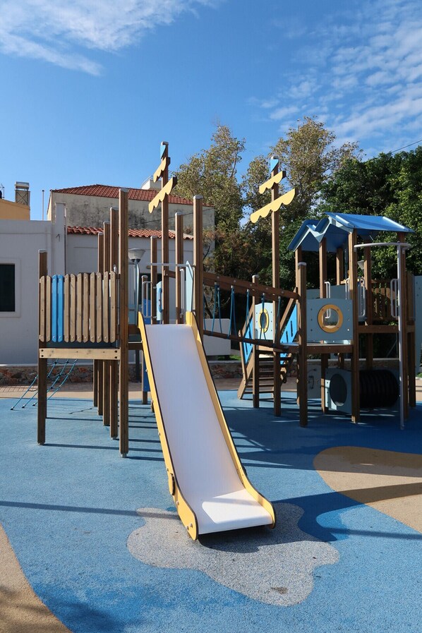A playground with a slide, climbing structures, and a playhouse.