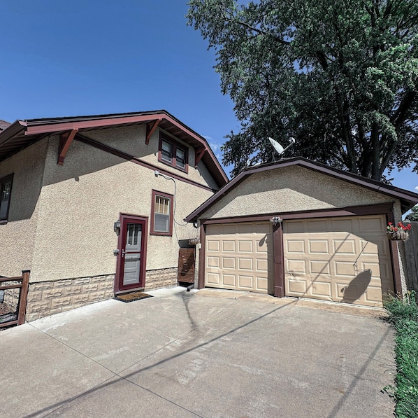 A two-story house with a garage, a red door, and a satellite dish.