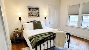 A bedroom with a bed, bedside lamps, a ceiling fan, a window with blinds, and a door. - Bricks - Main floor 2 bed/bath home, 2 car garage 3 blocks from Mayo Clinic! (Rochester)