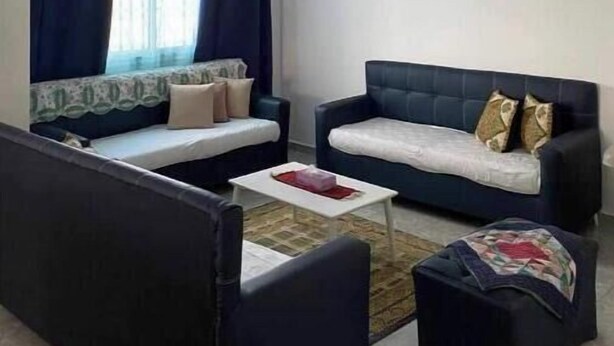 A living room with a sofa set, a coffee table, and a window with curtains. - A villa on the waterfront (Kerkouane)