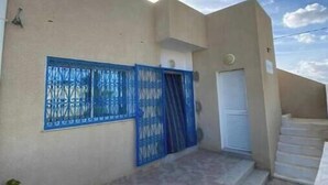 A building with a blue gate, a white door, and a staircase leading to an upper level. - A villa on the waterfront (Kerkouane)