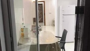 A modern kitchen with white cabinets and a refrigerator. - Appartement Kelibia (Kerkouane)