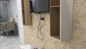 A modern living room with a mounted TV, white console table, and a marble floor. - Appartement Kelibia (Kerkouane)