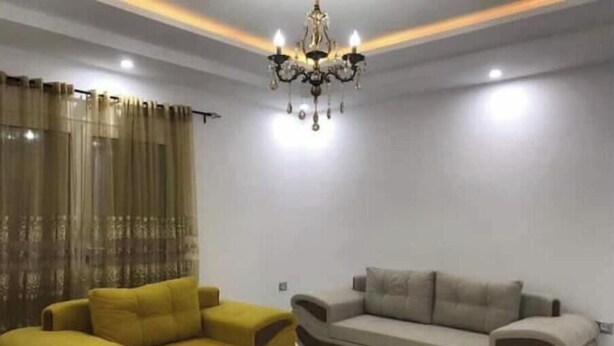 A living room with a yellow sofa, a grey sofa, and a white coffee table. - Appartement Kelibia (Kerkouane)