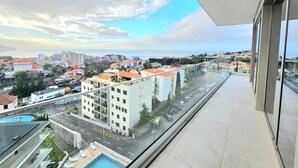 A balcony with a clear view of a cityscape, including buildings and a road.
