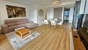A modern living room with a sofa, coffee table, and dining area with chairs.