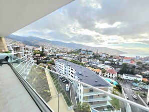A high-rise building with a balcony overlooking a cityscape, including roads and distant mountains. - Beautiful View by Rentallido (Funchal)