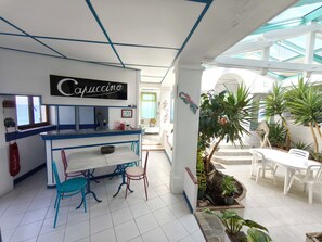 Une cuisine moderne avec un coin bar, un espace repas avec des chaises et un petit jardin avec des plantes.