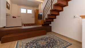 A staircase leading to a living area with a sofa and a television. - El Zirum-Boscoverde 3 (Rocca Pietore)