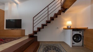 A staircase leading to a second floor, a washing machine, a television, and a patterned rug. - El Zirum-Boscoverde 3 (Rocca Pietore)