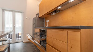 A kitchen with wooden cabinets, a built-in dishwasher, and a stainless steel refrigerator. - El Zirum-Boscoverde 3 (Rocca Pietore)