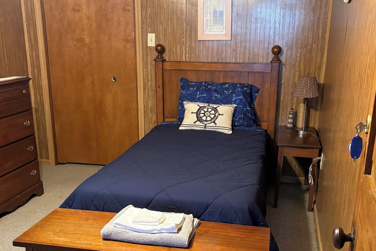 Une chambre à coucher avec un lit en bois, une commode en bois, une table de chevet avec une lampe et une porte dotée d’un trou de serrure.