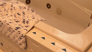 Una vasca da bagno con parete sagomata e un asciugamano.