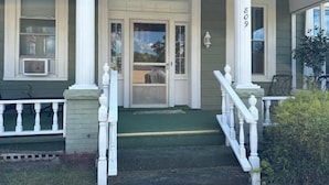 Una casa a due piani con un portico, una porta verde e il numero 809 sulla parete.