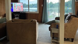 Un salon avec une télévision, un canapé et une vue sur un lac.