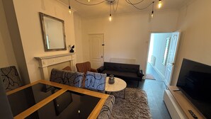 Una sala moderna con una mesa de centro de vidrio, un sofá, un televisor y una chimenea.